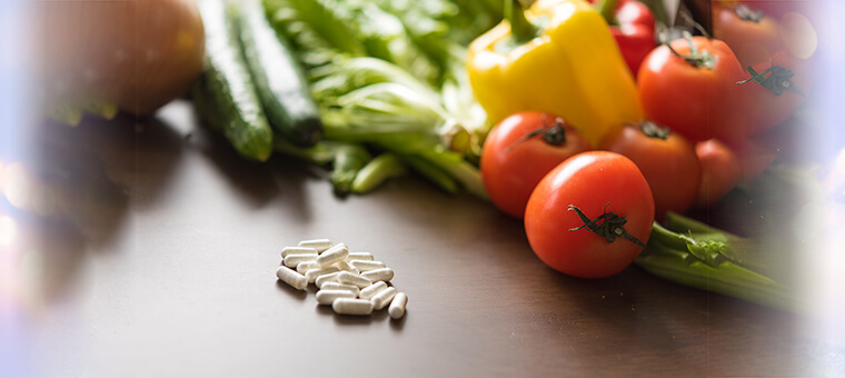 トマト、キュウリ、パプリカなどの野菜と、薬がテーブルの上に並べられている写真
